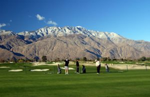 Golfers playing with mountains in background 